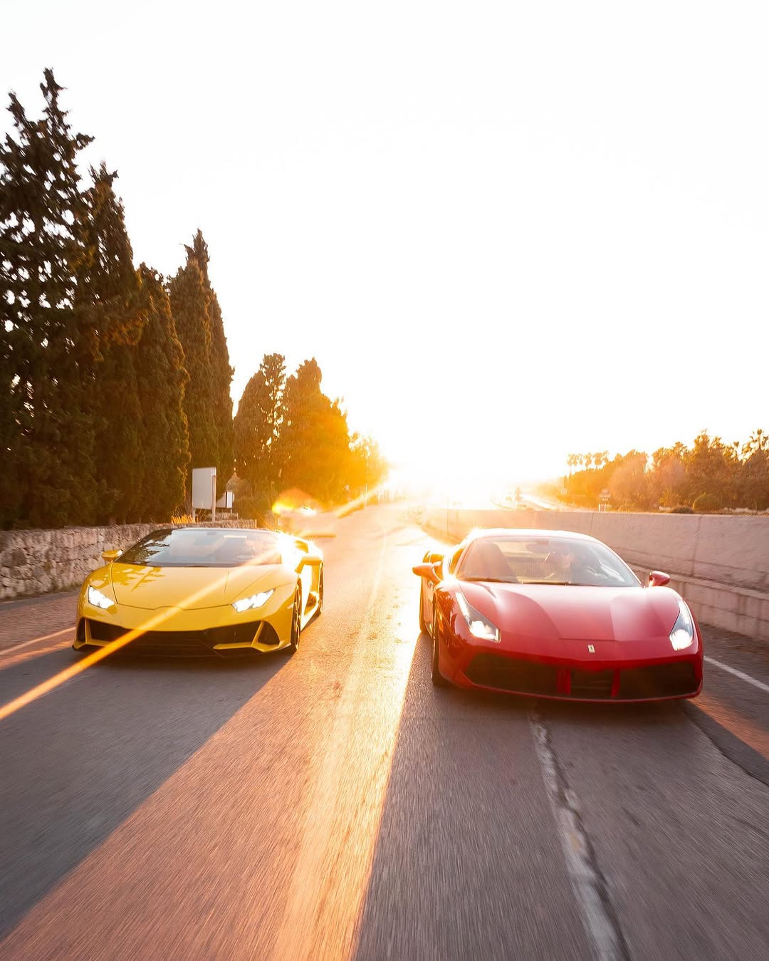 Lamborghini Huracán amarillo y Ferrari 488 rojo circulando al atardecer